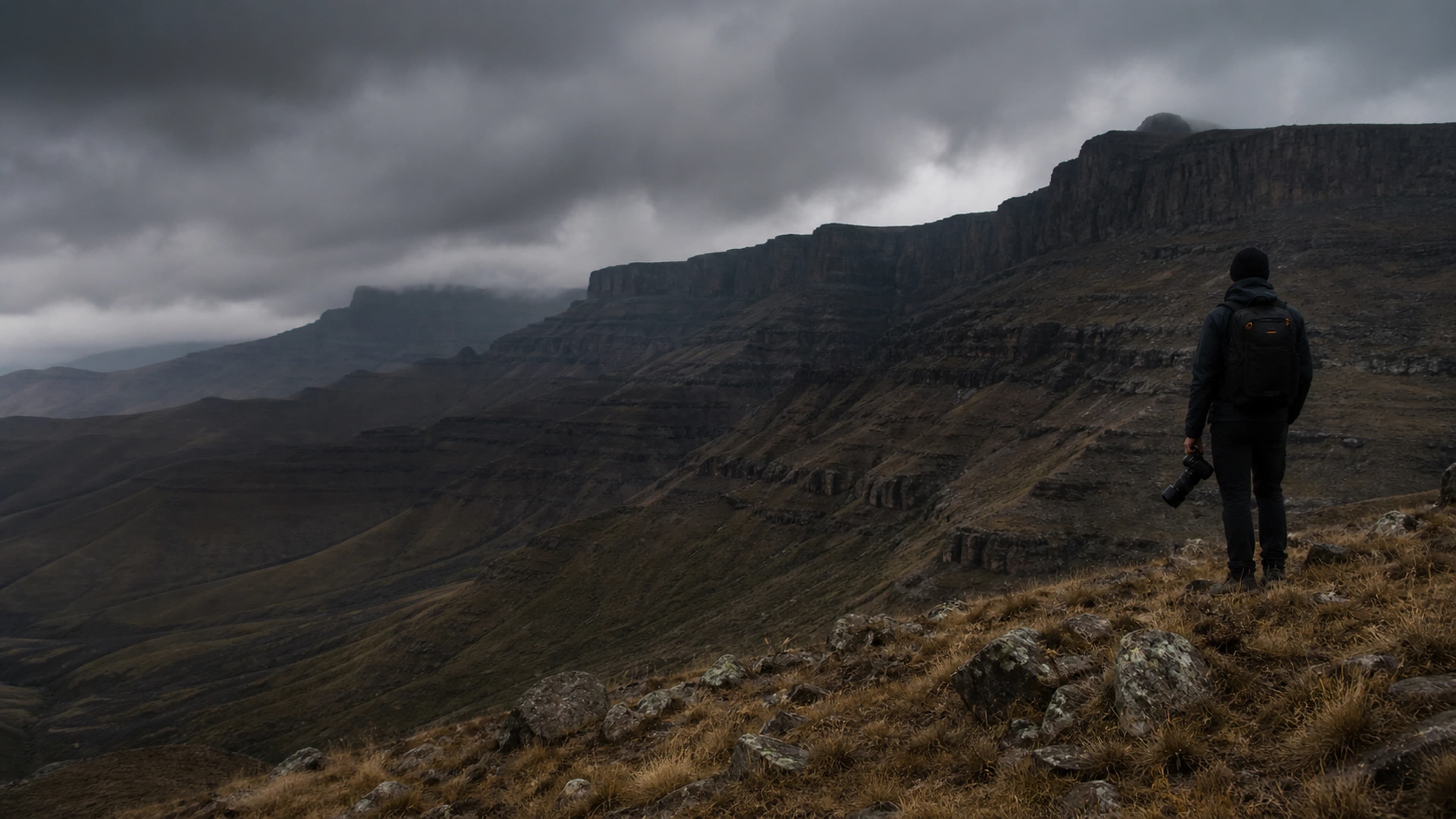 A field operator carrying a camera in the Drakensberg mountains